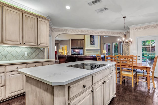 kitchen with black electric stovetop, tasteful backsplash, decorative light fixtures, an inviting chandelier, and a center island