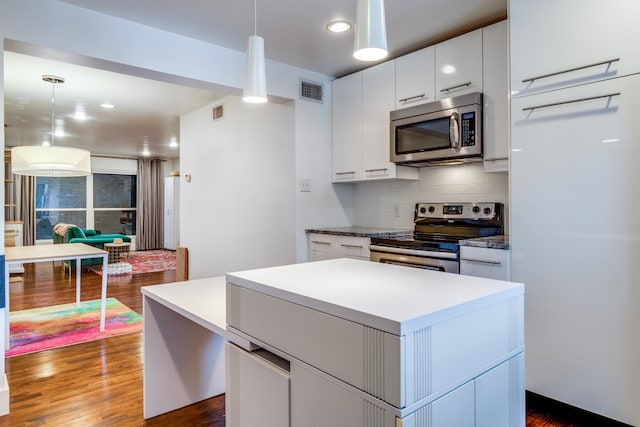 kitchen with stainless steel appliances, dark hardwood / wood-style floors, decorative light fixtures, and white cabinetry