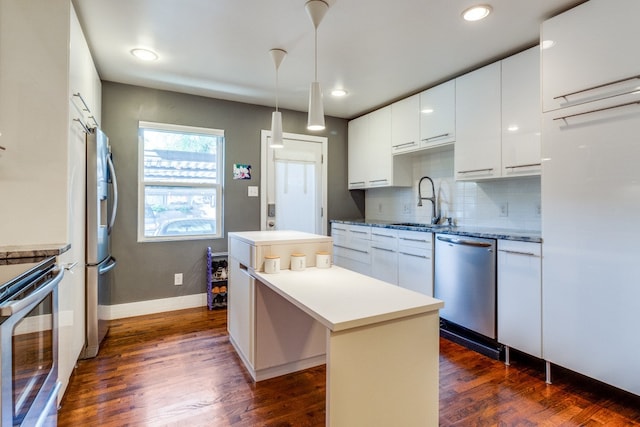 kitchen featuring dark hardwood / wood-style flooring, hanging light fixtures, white cabinets, appliances with stainless steel finishes, and a center island