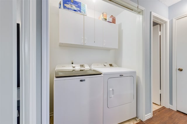 clothes washing area featuring cabinets, hardwood / wood-style flooring, a textured ceiling, and washer and clothes dryer