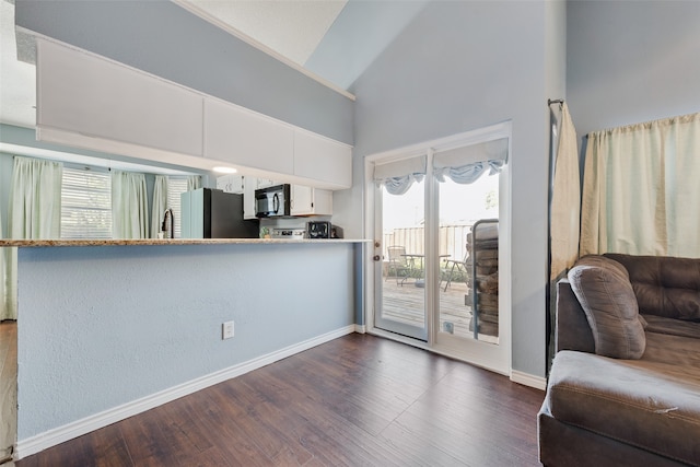 kitchen featuring stainless steel fridge, dark hardwood / wood-style floors, kitchen peninsula, and white cabinetry