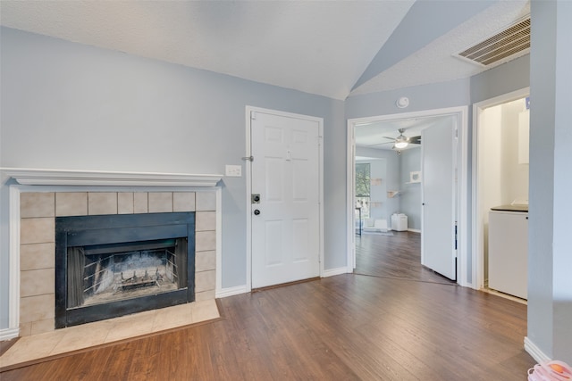 unfurnished living room featuring a tiled fireplace, ceiling fan, lofted ceiling, hardwood / wood-style flooring, and a textured ceiling