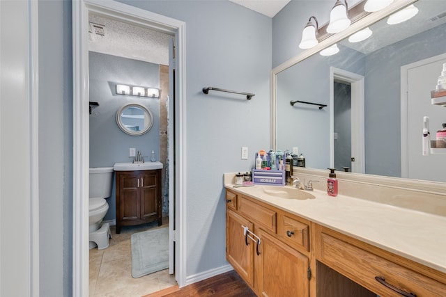 bathroom with tile patterned floors, toilet, vanity, and a textured ceiling