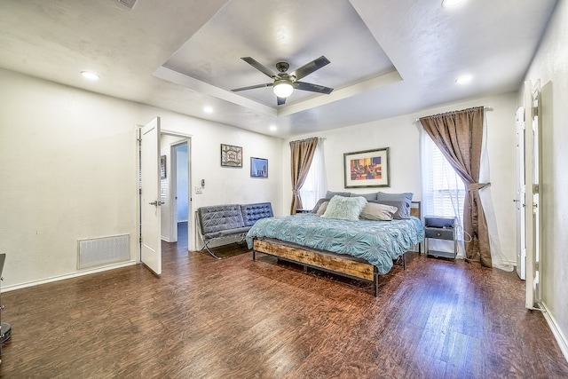 bedroom featuring ceiling fan, a tray ceiling, and dark hardwood / wood-style flooring