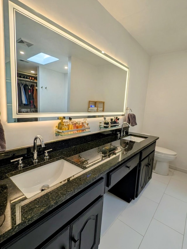 bathroom with toilet, vanity, and tile patterned flooring