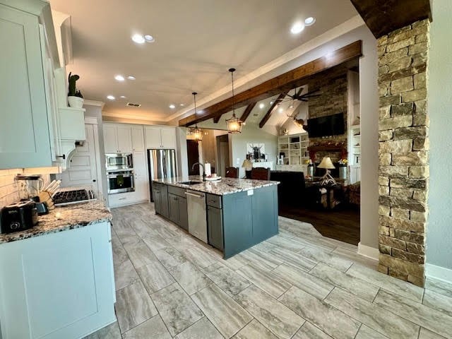 kitchen with ceiling fan, sink, decorative light fixtures, a kitchen island with sink, and appliances with stainless steel finishes