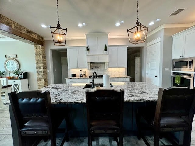 kitchen featuring appliances with stainless steel finishes, pendant lighting, a breakfast bar, and white cabinets