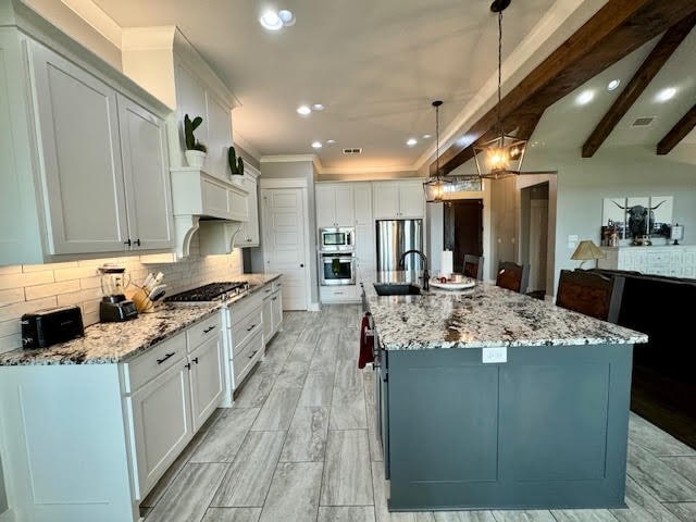 kitchen featuring appliances with stainless steel finishes, decorative light fixtures, white cabinetry, and a spacious island