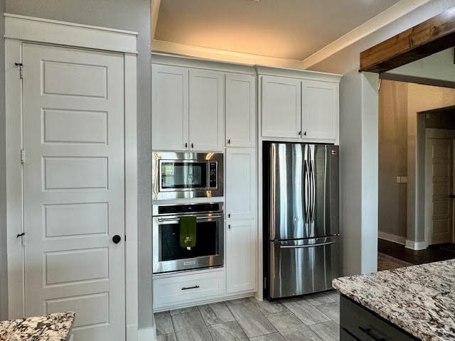 kitchen featuring light stone counters, white cabinets, stainless steel appliances, and light hardwood / wood-style flooring