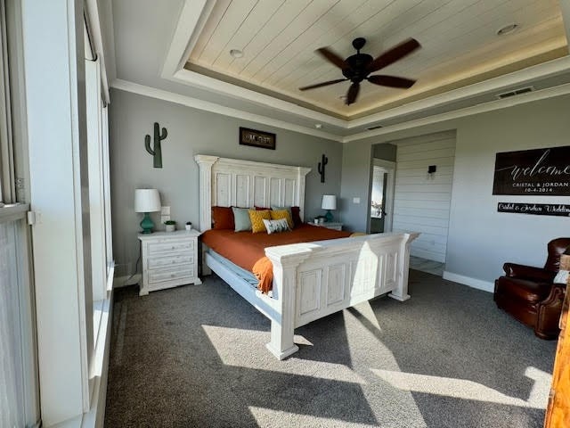 bedroom with a raised ceiling, wood ceiling, dark carpet, and ceiling fan