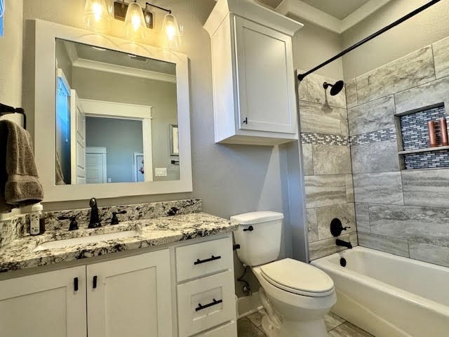 full bathroom featuring toilet, vanity, and tiled shower / bath