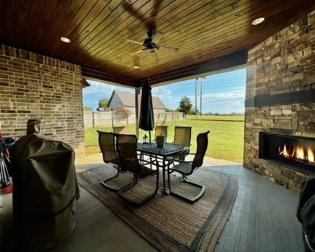 view of patio with an outdoor stone fireplace, ceiling fan, and a grill