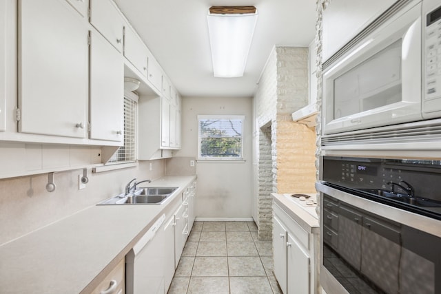 kitchen featuring white appliances, sink, light tile patterned floors, and white cabinets