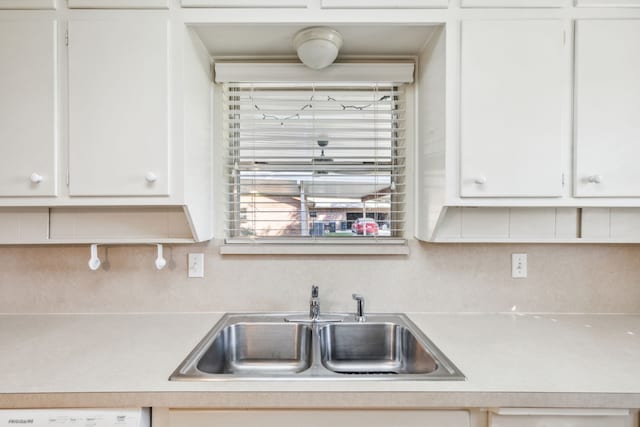 kitchen featuring washer / dryer, backsplash, sink, and white cabinetry