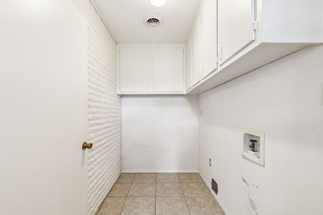 clothes washing area with washer hookup, brick wall, cabinets, and light tile patterned floors