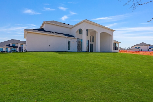 back of property with a yard and stucco siding