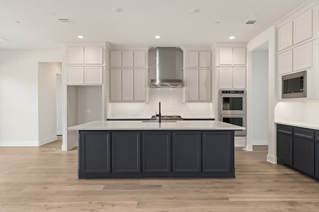 kitchen featuring white cabinets, wall chimney exhaust hood, visible vents, and stainless steel appliances