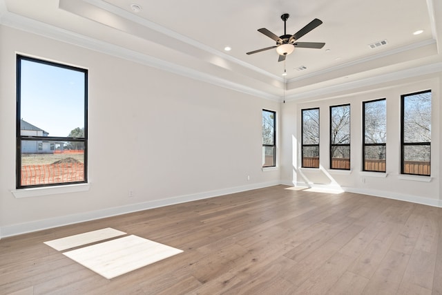 unfurnished room featuring light wood finished floors, visible vents, a wealth of natural light, and a tray ceiling