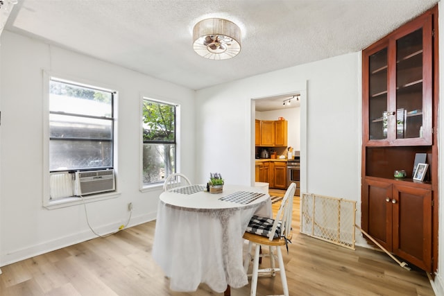 dining area with cooling unit, light hardwood / wood-style floors, and a textured ceiling