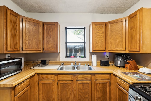 kitchen with appliances with stainless steel finishes, sink, and a textured ceiling