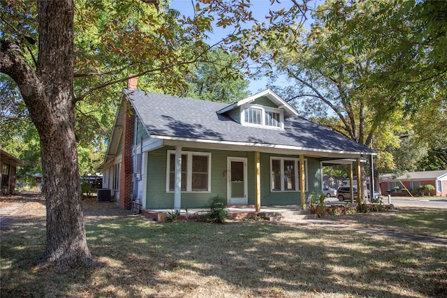 view of front of home with a front yard, central AC unit, and a porch