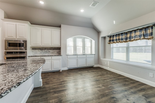 kitchen featuring dark wood-type flooring, tasteful backsplash, stone countertops, appliances with stainless steel finishes, and white cabinets