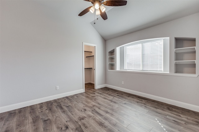 unfurnished bedroom featuring lofted ceiling, ceiling fan, a spacious closet, a closet, and light wood-type flooring