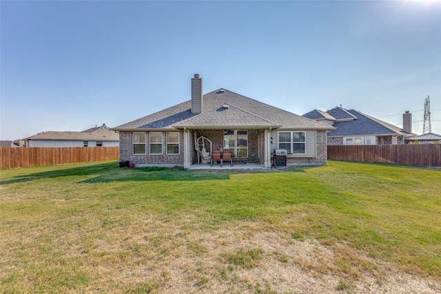 rear view of house featuring a lawn and a patio