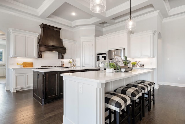 kitchen with an island with sink, appliances with stainless steel finishes, custom exhaust hood, and white cabinetry