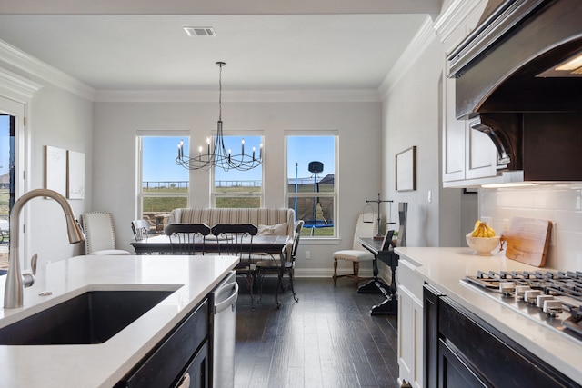 kitchen featuring hanging light fixtures, stainless steel appliances, decorative backsplash, sink, and an inviting chandelier