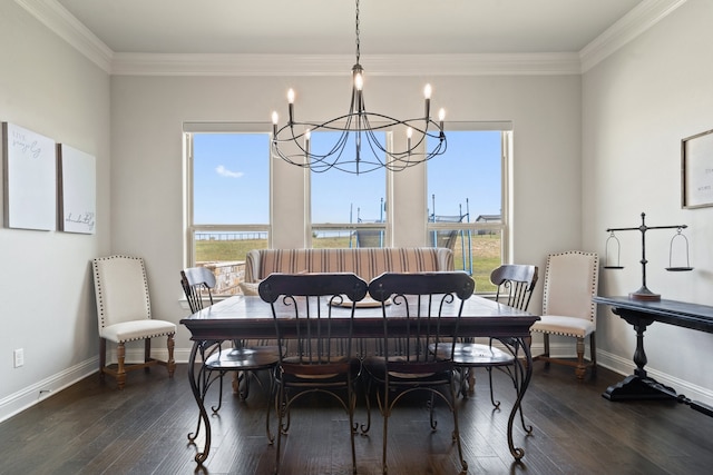 dining space featuring dark wood-type flooring, crown molding, and a chandelier