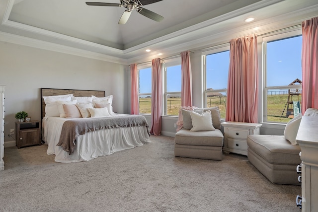 carpeted bedroom with ceiling fan, ornamental molding, and a raised ceiling