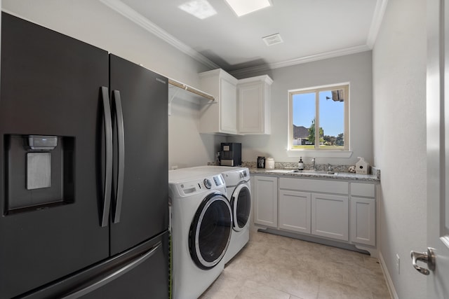 clothes washing area featuring cabinets, ornamental molding, washer and clothes dryer, and sink