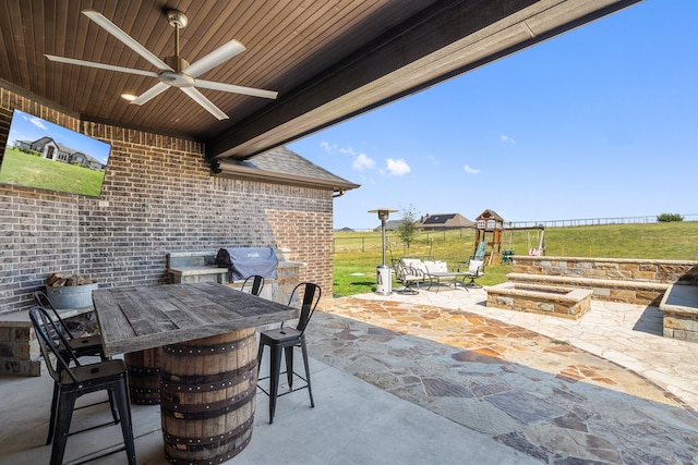 view of patio / terrace featuring a bar, ceiling fan, and a playground