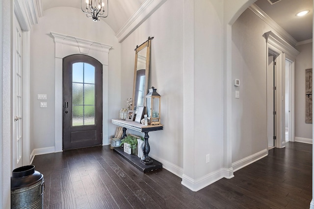 foyer entrance featuring vaulted ceiling, dark hardwood / wood-style floors, a notable chandelier, a barn door, and ornamental molding