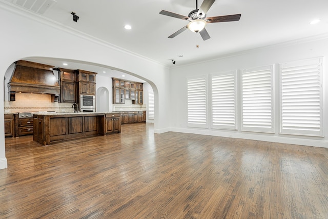 unfurnished living room featuring crown molding, ceiling fan, dark hardwood / wood-style flooring, and sink