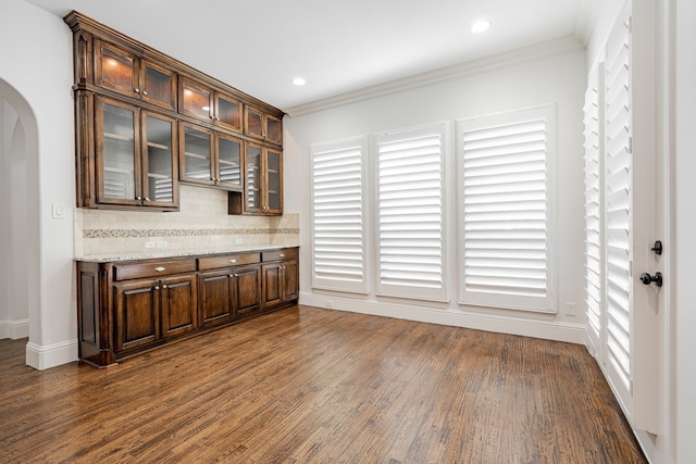 bar featuring dark brown cabinetry, dark hardwood / wood-style floors, light stone countertops, and decorative backsplash