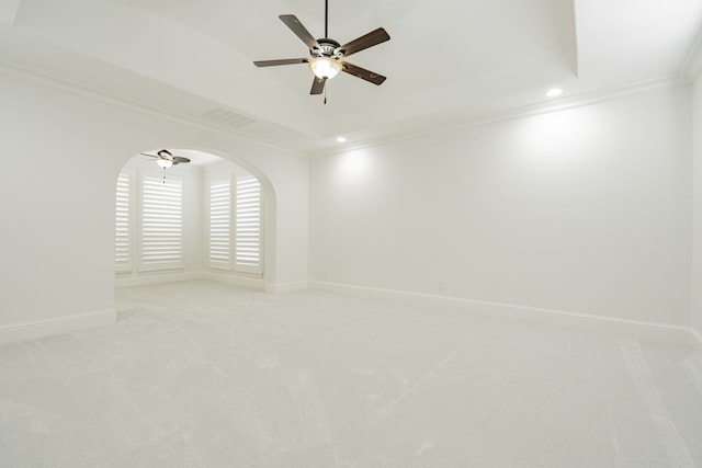 carpeted spare room featuring a raised ceiling, ornamental molding, and ceiling fan