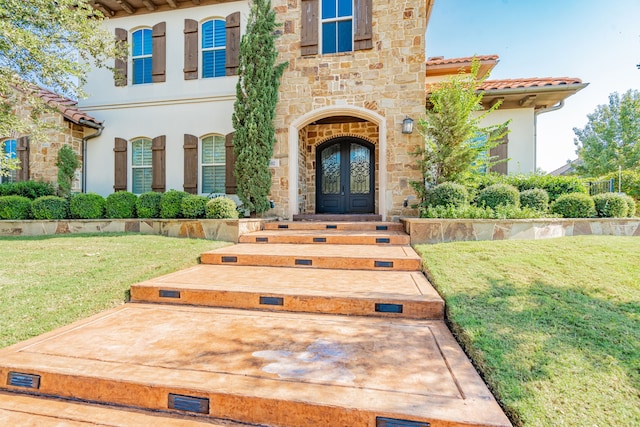 doorway to property featuring a lawn and french doors