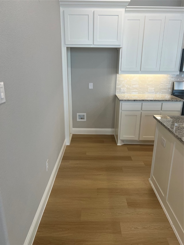 kitchen featuring white cabinets, tasteful backsplash, light stone countertops, light hardwood / wood-style flooring, and stainless steel range