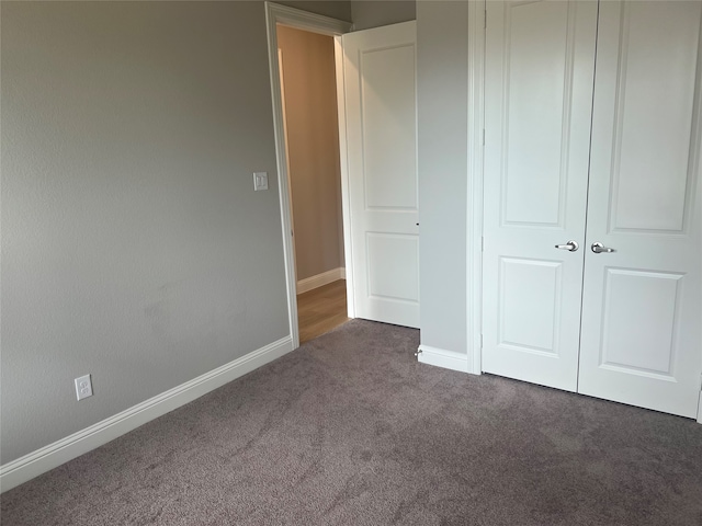 unfurnished bedroom with a closet and dark carpet