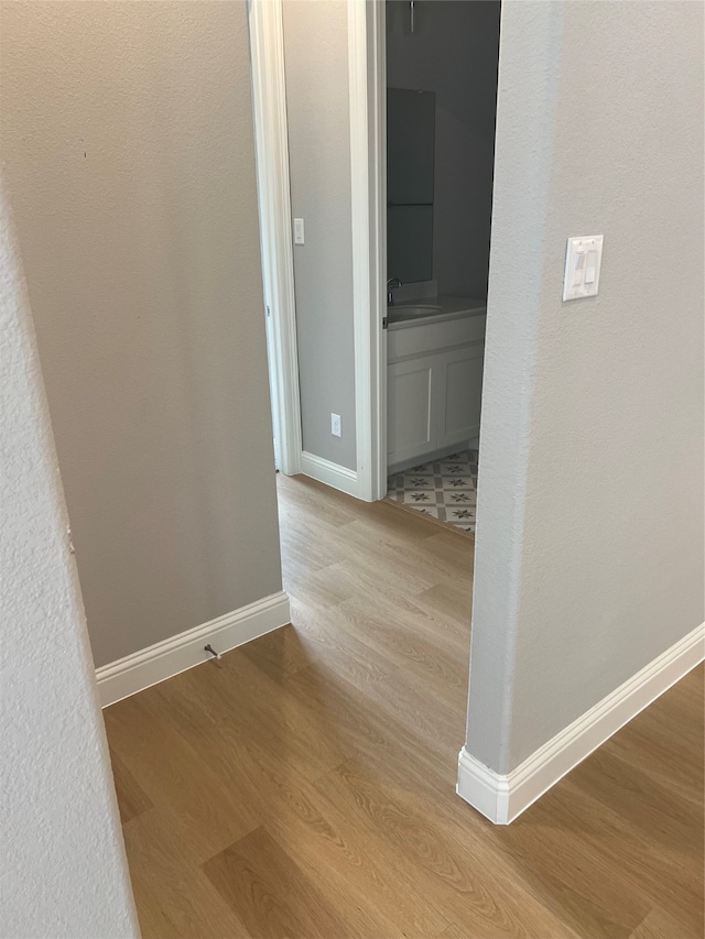 hallway with light hardwood / wood-style floors and sink