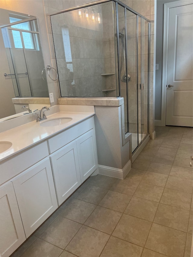 bathroom with a shower with door, vanity, and tile patterned flooring