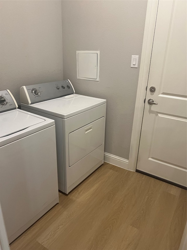 laundry area featuring washing machine and clothes dryer and light wood-type flooring