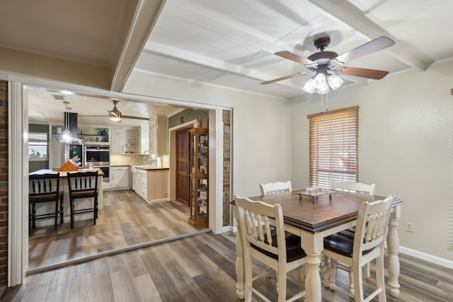 dining room featuring a wealth of natural light, light wood-type flooring, and beamed ceiling