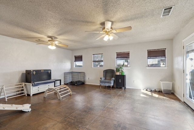 living area with a ceiling fan, visible vents, a textured ceiling, and baseboards