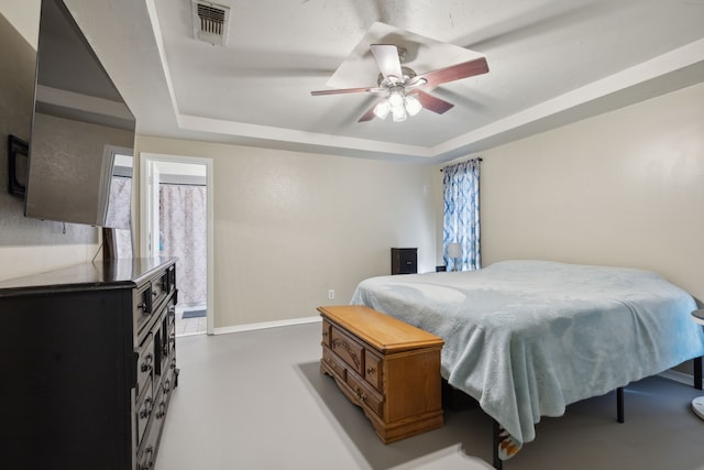 bedroom with ceiling fan, a raised ceiling, visible vents, and baseboards