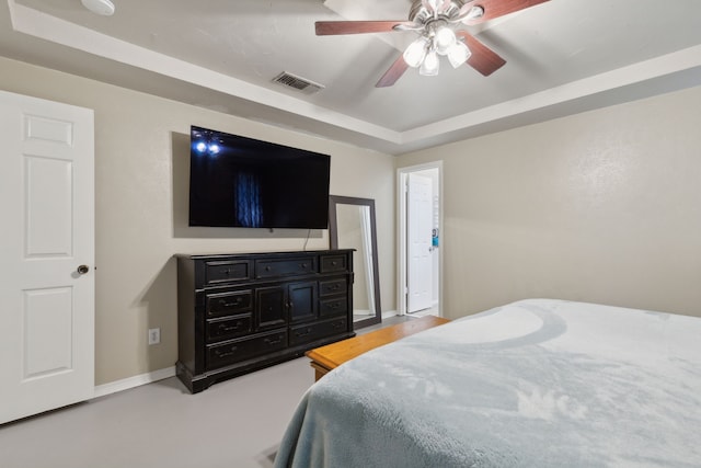 bedroom with baseboards, visible vents, a raised ceiling, and a ceiling fan