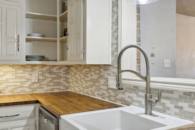 kitchen featuring backsplash, stainless steel dishwasher, sink, white cabinets, and butcher block counters