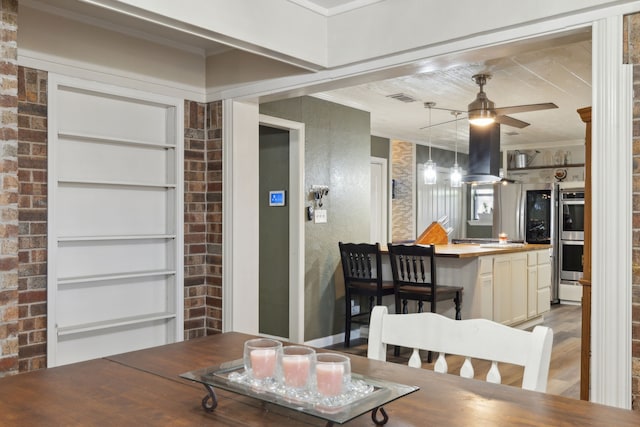 dining area featuring ornamental molding, visible vents, ceiling fan, and wood finished floors